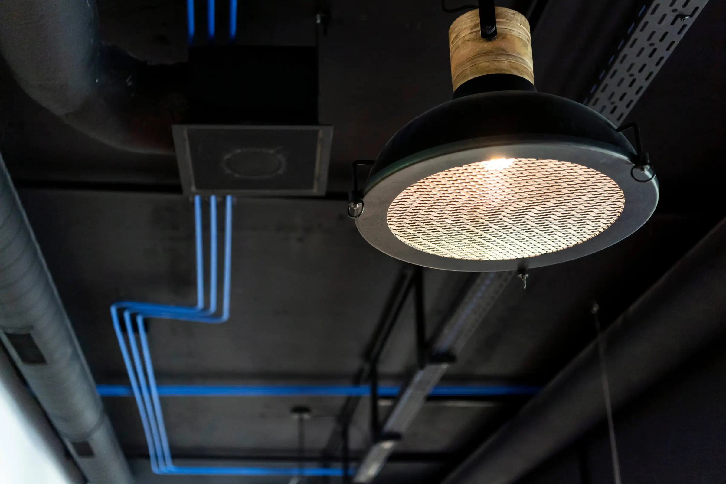 Industrial ceiling of the Monostream office with tungsten lamp and blue cable runs
